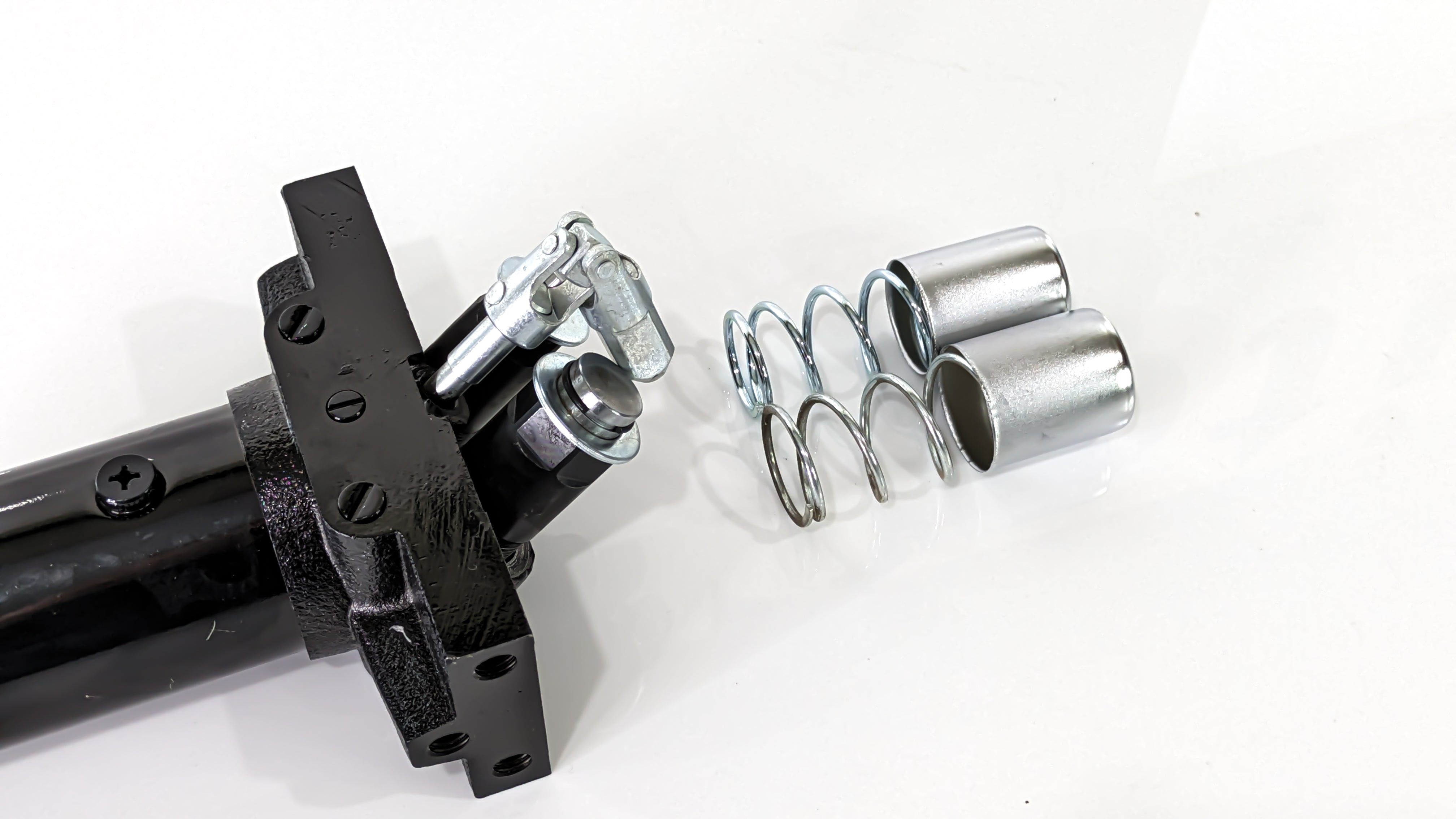 Replacement pump unit for a black rugged floor jack, consisting of metal springs, bolts, and other components.